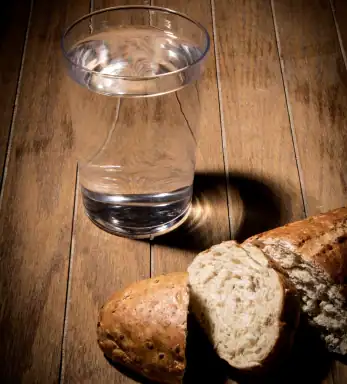 Glass of water and bread representing water fasting and calorie restriction